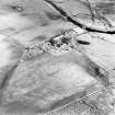 Oblique aerial view centred on the farmstead and the remains of the building, taken from the W