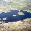 General oblique aerial view centred on the remains of the dun and the buildings looking towards the crofting township of Dunganachy and to Benbecula Aerodrome beyond, taken from the SE