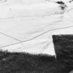 Oblique aerial view of Buntait centred on the remains of a hut-circle and rig with small cairns and a field bank adjacent, taken from the NNE.