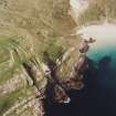 Oblique aerial view of Feall Bay centred on the remains of a fort, cairn, clearance cairns and rig, taken from the NNW.