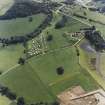 Oblique aerial view centred on the remains of the chambered cairn with farmsteading adjacent, taken from the N.