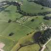 Oblique aerial view centred on the remains of the chambered cairn with farmsteading adjacent, taken from the WNW.