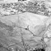 Corrymuckloch, oblique aerial view, taken from the SSW, showing the Crieff to Dalnacardoch military road running across the centre of the photograph. An area of hut-circles, clearance cairns and field banks is visible in the centre. A hoard find spot, in peat cuttings, is visible as a dark patch in the centre of the photograph.