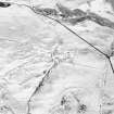 Oblique aerial view centred on the remains of the farmstead and enclosure with field-system adjacent, taken from the SE.