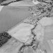 Oblique aerial view of Dunning centred on the cropmarks of a Roman temporary camp and the village, taken from the NNW.