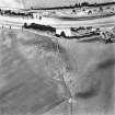Oblique aerial view of Broxy Kennels centred on the cropmarks of a fort, taken from the W.