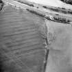 Oblique aerial view centred on the cropmarks of the fort, taken from the WSW.