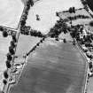 Oblique aerial view centred on the cropmarks of the unenclosed settlement with church and smithy adjacent, taken from the NE.