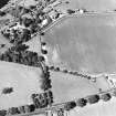 Oblique aerial view centred on the cropmarks of the unenclosed settlement with church and smithy adjacent, taken from the SSE.