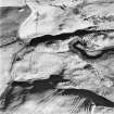 Oblique aerial view centred on the remains of hut-circles with rig and enclosures adjacent, taken from the WSW.