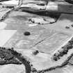 Oblique aerial view centred on the cropmarks of an enclosure and trackways with round house, enclosure, pits, cultivation remains, pit-alignment and long barrow adjacent, taken from the NE.