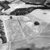 Oblique aerial view centred on the cropmarks of an enclosure and trackways with round house, enclosure, pits, cultivation remains, pit-alignment long barrow, square barrow and plantation bank adjacent, taken from the NW.