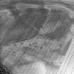 Oblique aerial view centred on the cropmarks of the quarry pits flanking a Roman Road with linear cropmarks and unenclosed settlement adjacent, taken from the SW.