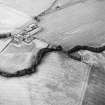 Oblique aerial view of The Welton centred on the cropmarks of a fort with unenclosed settlement, souterrains, barrows, possible enclosure and farmhouse adjacent, taken from the SW.