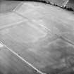 Oblique aerial view centred on the cropmarks of the ring-ditches and rig, taken from the NNE.