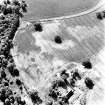 Rossie, oblique aerial view, taken from the NE, centred on a series of indeterminate cropmarks and the marks of an enclosure and a trackway. Rossie Church is visible in the bottom centre of the photograph.