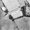 Oblique aerial view centred on the cropmarks of an enclosure and unenclosed settlement.
