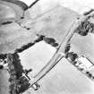 Oblique aerial view centred on the cropmarks of an enclosure and unenclosed settlement.