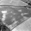 Pusk Wood, oblique aerial view, taken from the N, centred on cropmarks of cultivation remains,  with a possible souterrain to the right of the photograph and a possible sunken floored house to the bottom of the photograph.