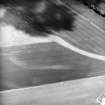 Oblique aerial view centred on the cropmarks of the ring-ditches and rig, taken from the W.