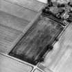 Oblique aerial view centred on the cropmarks of the ring-ditch with Ravensby House adjacent, taken from the NE.