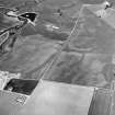 Oblique aerial view centred on the cropmarks of the square barrow, roundhouse, sunken floored building, linear cropmarks, unenclosed settlement, rig, enclosure and other cropmarks, taken from the SW.