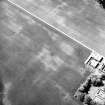 Newbigging, oblique aerial view, taken from the ESE, centred on the cropmarks of an enclosure, pits and an unenclosed settlement. The cropmark of a barrow is visible in the top centre of the photograph.