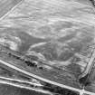 Oblique aerial view of Purlieknowe centred on the cropmarks of a pit-defined cursus with linear cropmarks and a possible pit-alignment adjacent, taken from the ESE.