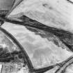 Raeburnfoot, oblique aerial view, taken from the WNW, centred on the bank barrow. Raeburnfoot Roman Fort, and enclosures at Kiln Syke, are visible in the top half of the photograph.