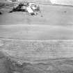 Oblique aerial view centred on the cropmarks of the fort with the farmsteading adjacent, taken from the SE.