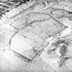 Oblique aerial view centred on the remains of the farmstead, rig, enclosures and quarry, taken from the NNE.