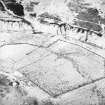 Oblique aerial view centred on the remains of the farmstead, rig, enclosures and quarry, taken from the WNW.