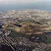 Oblique aerial view of Edinburgh centred on Holyrood Park, taken from the SSW.