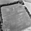 Castlesteads, oblique aerial view, taken from the ENE, centred on the cropmarks of a pit alignment and enclosure. A dovecot is visible in the top centre of the photograph.