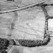 Oblique aerial view centred on the cropmarks of the pit-alignment with the cropmarks of the square pit and the rig and the farmsteading adjacent, taken from the SE.