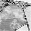 Carrington Mill, enclosure: oblique aerial view taken from the SE, centred on the cropmarks of an enclosure.  The village (burgh) of Carrington is visible in the top right of the photograph.