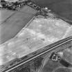 Westfield, Inveresk, oblique aerial view, taken from the SSW, centred on the cropmarks of ditches of the W side of the cursus monument, crossed by the cropmark of a dismantled mineral railway.