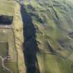 Oblique aerial view centred on the remains of the settlement with the palisaded enclosure adjacent, taken from the ENE.