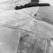 Oblique aerial view of Headshaw centred on the cropmarks of a fort, taken from the SW.