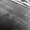 Oblique aerial view centred on the cropmarks of the ring-ditch and possible unenclosed settlement with the cropmarks of the palisaded enclosure and rig adjacent, taken from the ESE.