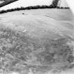 Oblique aerial view centred on the remains of the kerb cairn with rig adjacent, taken from the WNW.