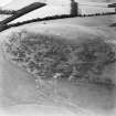 Oblique aerial view centred on the remains of the kerb cairn with rig adjacent, taken from the WNW.