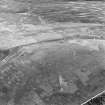Oblique aerial view centred on the remains of the fort and standing stone, taken from the W.