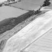 Oblique aerial view of hanging Craig centred on the cropmark of a fort, with the remains of Barnes Castle adjacent.  Taken from the SW.