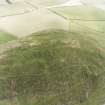 Oblique aerial view centred on the remains of the fort and cairn, taken from the N.