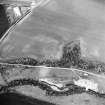 Oblique aerial view centred on the cropmarks of the fort, linear cropmark and cropmarks of the building, taken from the SE.