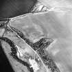 Oblique aerial view centred on the cropmarks of the fort, linear cropmark and cropmarks of the building, taken from the E.