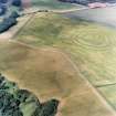Oblique aerial view centred on the cropmarks of the fort, field boundaries and cropmarks, taken from the S.