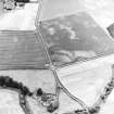 Eckford, oblique aerial view, taken from the NE, centred on the cropmarks of an enclosure suurrounding a barrow and pit-circle.