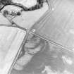 Eckford, oblique aerial view, taken from the WNW, centred on the cropmarks of an enclosure suurrounding a barrow and pit-circle.